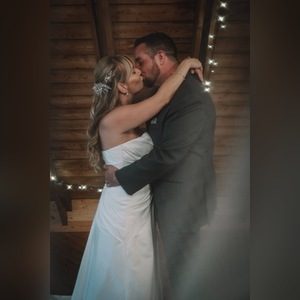Bride and groom kissing indoors beneath wooden beams and string lights
