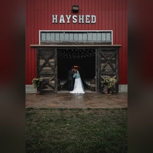 Bride and groom embracing in the open doorway of a red barn